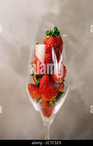 Primo piano di un bicchiere pieno di fragole intere parte anteriore di una parete grigia Foto Stock