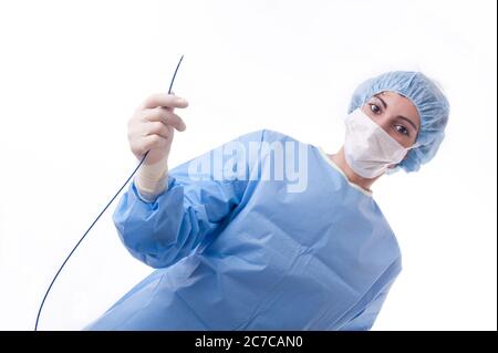 Medico o infermiere di sesso femminile che indossa una tuta o un abito sterile blu che tiene un catetere per l'ablazione per una procedura cardiaca. Foto Stock