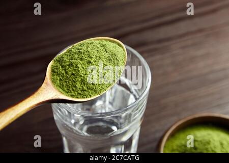 Cucchiaio con polvere di erba del siero liofilizzata per spremere il succo di disintossicazione. Concetto di stile di vita sano. Foto Stock