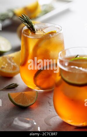 Tradizionale tè freddo con limone, lime e ghiaccio guarnito con rametti di rosmarino. Messa a fuoco selettiva. Foto Stock