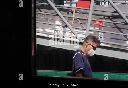 Hong Kong, CINA. 16 luglio 2020. Il barman mascherato che serve il molo di Star Ferry è visto dall'interno del traghetto. Hong Kong è sotto l'attacco della terza ondata di Coronavirus. Città è ancora una volta oscurata dal VIRUS, i cittadini sono allertati dalla persistenza del ceppo di coronavirus che non mostrano alcun segno di dissipazione.July-16, 2020 Hong Kong.ZUMA/Liau Chung-ren Credit: Liau Chung-ren/ZUMA Wire/Alamy Live News Foto Stock