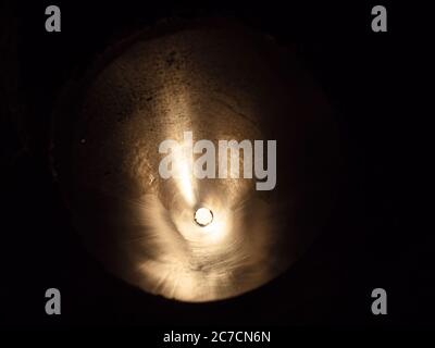 Ombre scure con luce in piccolo cerchio al centro . Vista attraverso il tubo lungo in acciaio. Foto Stock