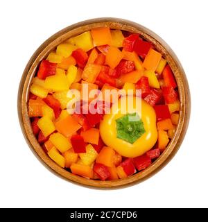 Testa di peperone e cialde a dadini in un recipiente di legno. Peperone dolce, capsicum, anche paprika, tagliato in patatine colorate. Frutta fresca gialla, arancione e rossa. Foto Stock