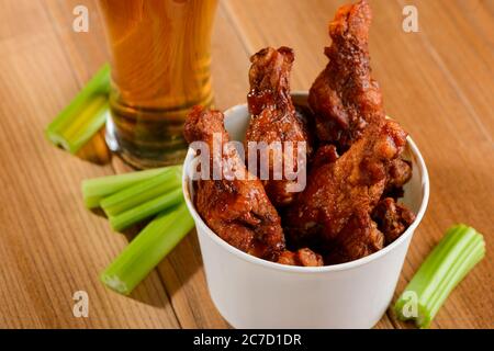 Appetitosi bastoncini di pollo fritti, fette di sedano e un bicchiere di birra Foto Stock