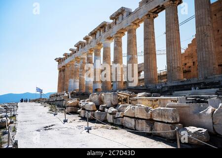 Le colonne del Partenone dell'Acropoli di Atene contro un cielo blu e la bandiera greca. Foto Stock