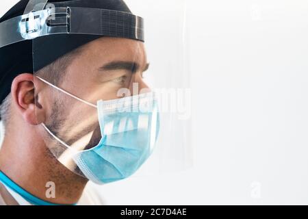 Medico che indossa la maschera chirurgica del viso ppe e visiera lotta contro l'epidemia di virus corona - concetto di assistenza sanitaria e operatori medici Foto Stock