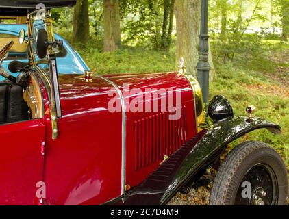 Primo piano di un'auto d'epoca rossa nella foresta durante il giorno Foto Stock