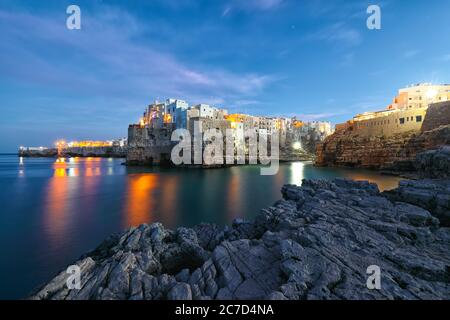 Scena notturna nel golfo di Cala Paura con Bastione di Santo Stefano in paese sulle rocce Polignano a Mare, Puglia, Italia, provincia di Bari. Foto Stock