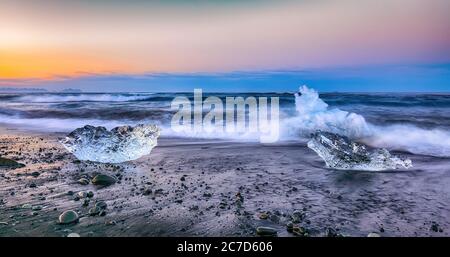 Incredibili pezzi dell'iceberg brillano sulla famosa Diamond Beach alla laguna di Jokulsarlon durante il tramonto. Ubicazione : Laguna di Jokulsarlon, Spiaggia di Diamante, V Foto Stock