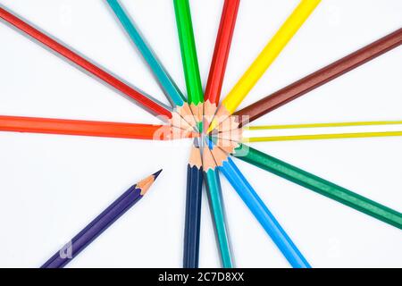 Diversi pastelli a matita di legno colorati posti su una carta bianca in un cerchio rotondo Foto Stock