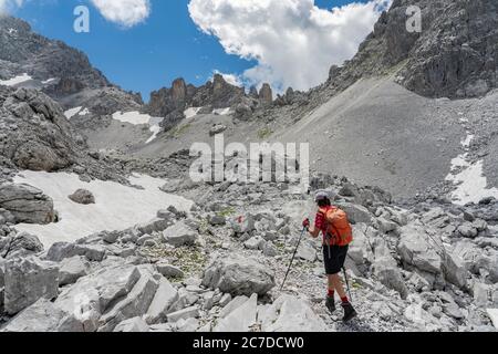 Donna anziana trekking nel terreno selvaggio sotto la Drosa Tor nelle montagne della valle di Montafon, Vorarlberg, Austria Foto Stock