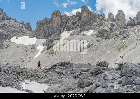 Donna anziana trekking nel terreno selvaggio sotto la Drosa Tor nelle montagne della valle di Montafon, Vorarlberg, Austria Foto Stock