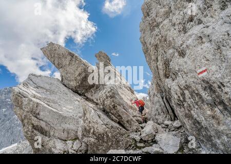 Donna anziana trekking nel terreno selvaggio sotto la Drosa Tor nelle montagne della valle di Montafon, Vorarlberg, Austria Foto Stock