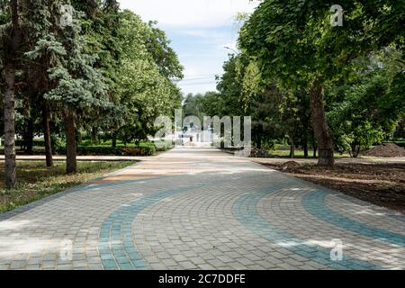 Posa di lastre di calcestruzzo colorate nel parco. I lavoratori professionisti che lavorano su muratori stanno installando nuove piastrelle e lastre per pavimentazione per marciapiede su piani Foto Stock