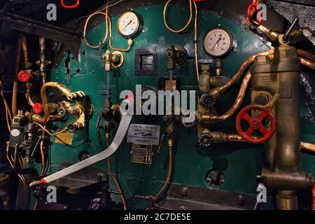Macchinario pesante in acciaio con valvole rosse arrugginite, contatori e tubi all'interno di un treno 1903 tipo 10 Foto Stock