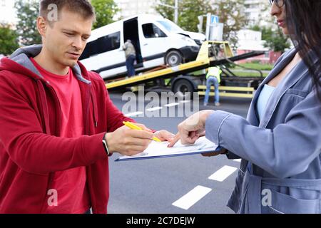 Uomo e donna compilano i documenti dopo un incidente d'auto. Foto Stock