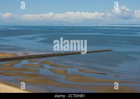 Un lungo molo che si estende nelle acque calme della Baia di Maputo, in una giornata di sole limpida, con bassa marea, nel sud del Mozambico Foto Stock