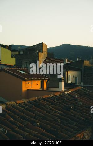 Immagine verticale di tetti rossi della casa con le montagne nel sfondo durante il giorno Foto Stock