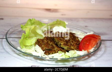 Cavolo cutlets vegetariano su un piatto trasparente su uno sfondo di legno chiaro Foto Stock