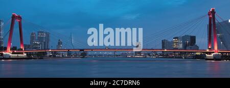 Ampio scatto di uno splendido ponte sospeso vicino a edifici alti di notte Foto Stock