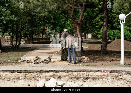 Moldavia, Tiraspol, 25 maggio 2020: I lavoratori posano lastre di pavimentazione in un parco Foto Stock