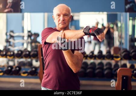 Un ritratto di calvo uomo anziano che fa l'allenamento prima di allenarsi in palestra. Concetto di persone, assistenza sanitaria e stile di vita Foto Stock