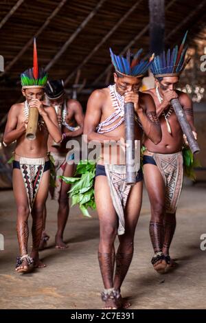 Uomini indigeni che soffiano su uno strumento tradizionale Foto Stock