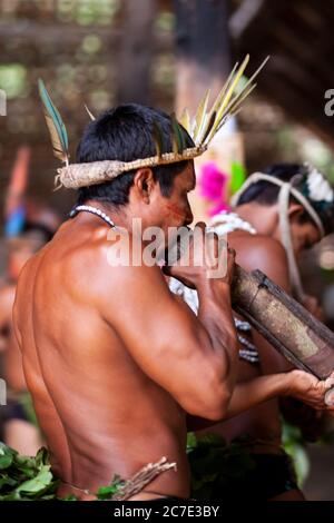Uomini indigeni che soffiano su uno strumento tradizionale Foto Stock