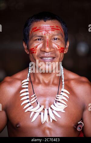 Ritratto di un uomo indigeno amazzonico con tradizionale vernice per il viso e una collana di denti tribali, che riflette il patrimonio culturale della cultura nativa del Brasile Foto Stock