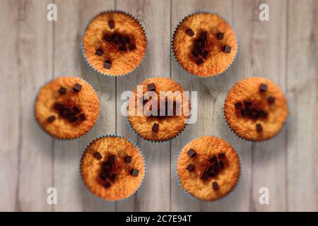 Un tocco orizzontale ad alta angolazione di deliziosi muffin con una cioccolata scheggiatura di una superficie di legno Foto Stock