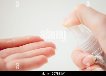 Mani femminili e gel igienizzante in un piccolo flacone di plastica. Foto Stock