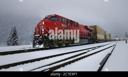 Motore del treno rosso che tira il carico nella neve Foto Stock