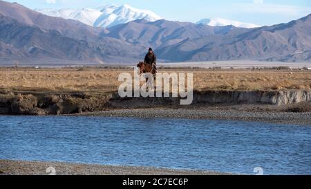 Un mandante kazako nomade a cavallo all'inizio dell'inverno nei Monti Altai, Mongolia occidentale. Foto Stock