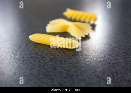 Colpo di primo piano orizzontale di tre diversi pezzi di macaroni su parte superiore di una superficie nera Foto Stock