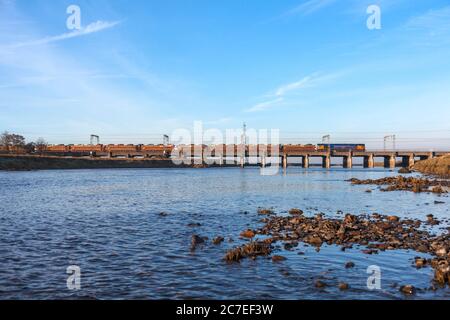 GB Railroad classe 66 locomotiva che attraversa il viadotto del ponte metallico a Mossband sulla linea principale della costa occidentale con un treno merci che trasporta auto nuove Foto Stock