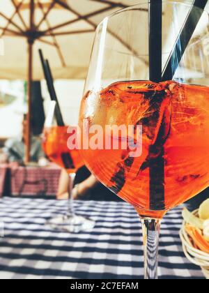 Colpo verticale di un cocktail rosso con cubetti di ghiaccio e. due cannucce su un tessuto a righe Foto Stock