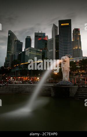 Immagine verticale della fontana Merlion mascotte di Singapore, con alti grattacieli sul retro Foto Stock