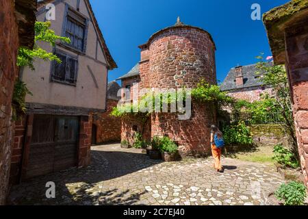 Una donna turistica a piedi nel villaggio di arenaria rossa Collonges-la-Rouge, Francia, Correze, Limousin, Europa Foto Stock