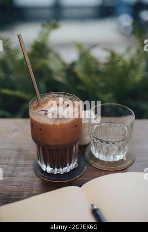 Inquadratura mirata selettiva ad alto angolo di un bicchiere da caffè ghiacciato con una cannuccia e un bicchiere vuoto Foto Stock