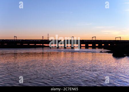 2 treni Vergine / Avanti costa ovest che attraversa il viadotto Esk fiume a Mossband sulla linea principale della costa ovest al tramonto Foto Stock