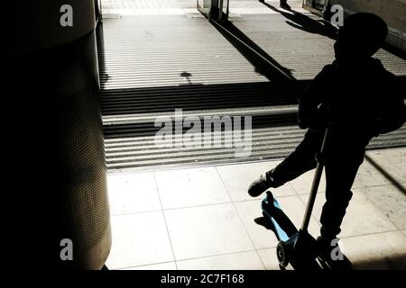 Silhouette di un ragazzino che guida uno scooter durante il giorno Foto Stock