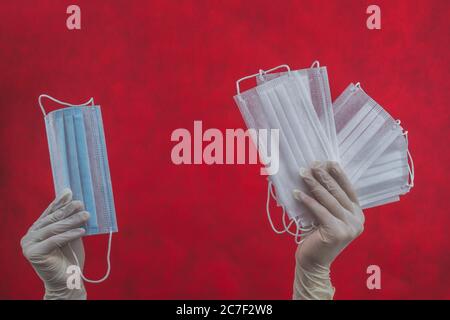 Maschere mediche in mani con protezione. Misure preventive contro malattie respiratorie e virus. Mano in guanto chirurgico bianco contiene maschere monouso Foto Stock