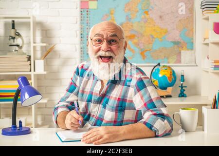 Insegnante maturo in classe. Insegnante allegro che ama il suo lavoro. Divertente vecchio professore. Insegnante sorridente. Foto Stock