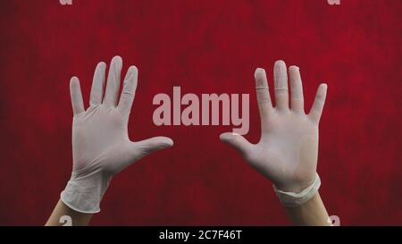 Mani in guanti protettivi. Palmi delle mani in guanti medici. Su fondo rosso Foto Stock