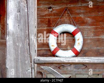 Life Buoy attaccato alla vecchia parete rivestita in legno Foto Stock