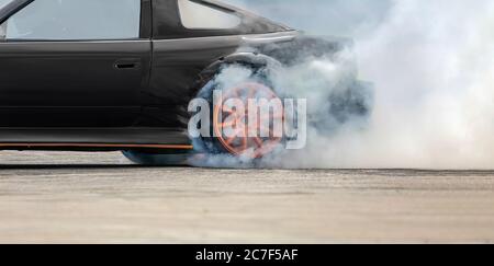 Auto da corsa che brucia pneumatici sulla pista di velocità Foto Stock