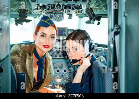 Trainee pilota e istruttore di volo in un box aereo. Desidera un volo di successo. Ragazze giovani in aereo. Piloti in cabina. Donna che tiene Foto Stock