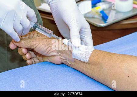 Siringa a pressione del medico nel tappo eparina mano del paziente Foto Stock