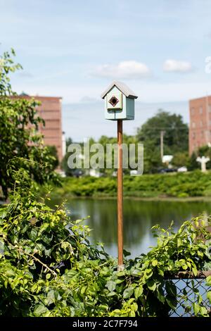 Una casa degli uccelli presso Water Street e il parco francese rinascimentale con ex mulini tessili lungo il fiume Nashua a Nashua, New Hampshire, Stati Uniti. Foto Stock