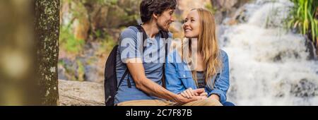 Coppia di turisti con uno zaino sullo sfondo di una bandiera cascata, FORMATO LUNGO Foto Stock